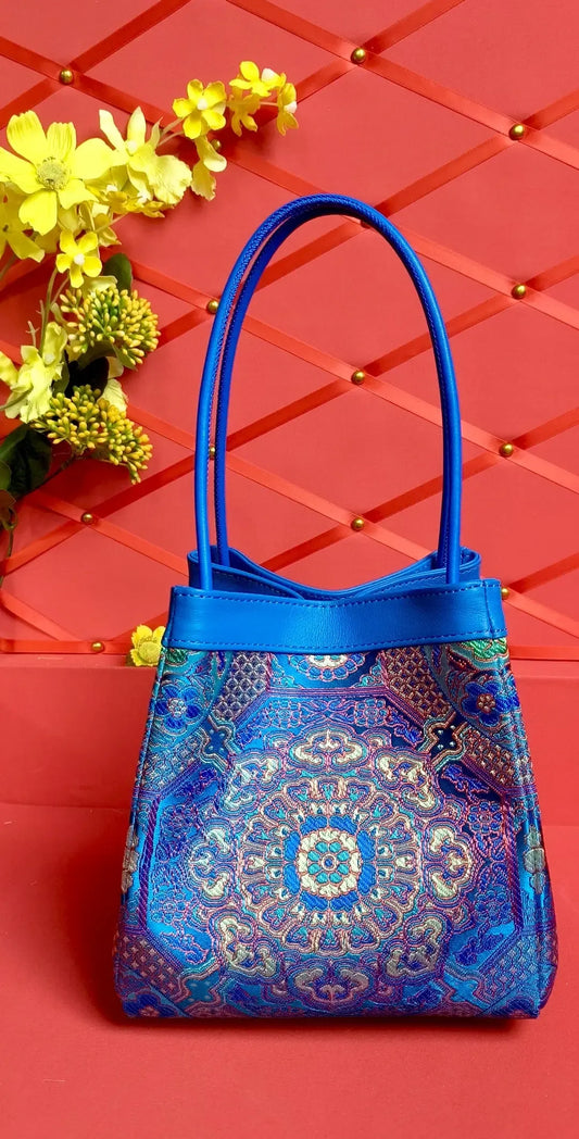 Sinodreams ARC Classics – Imperial Sky – handgefertigte Brokat‑Handtasche mit blauem Premium‑Leder, feinen Ornamenten und kompakter, femininer Arc‑Form.