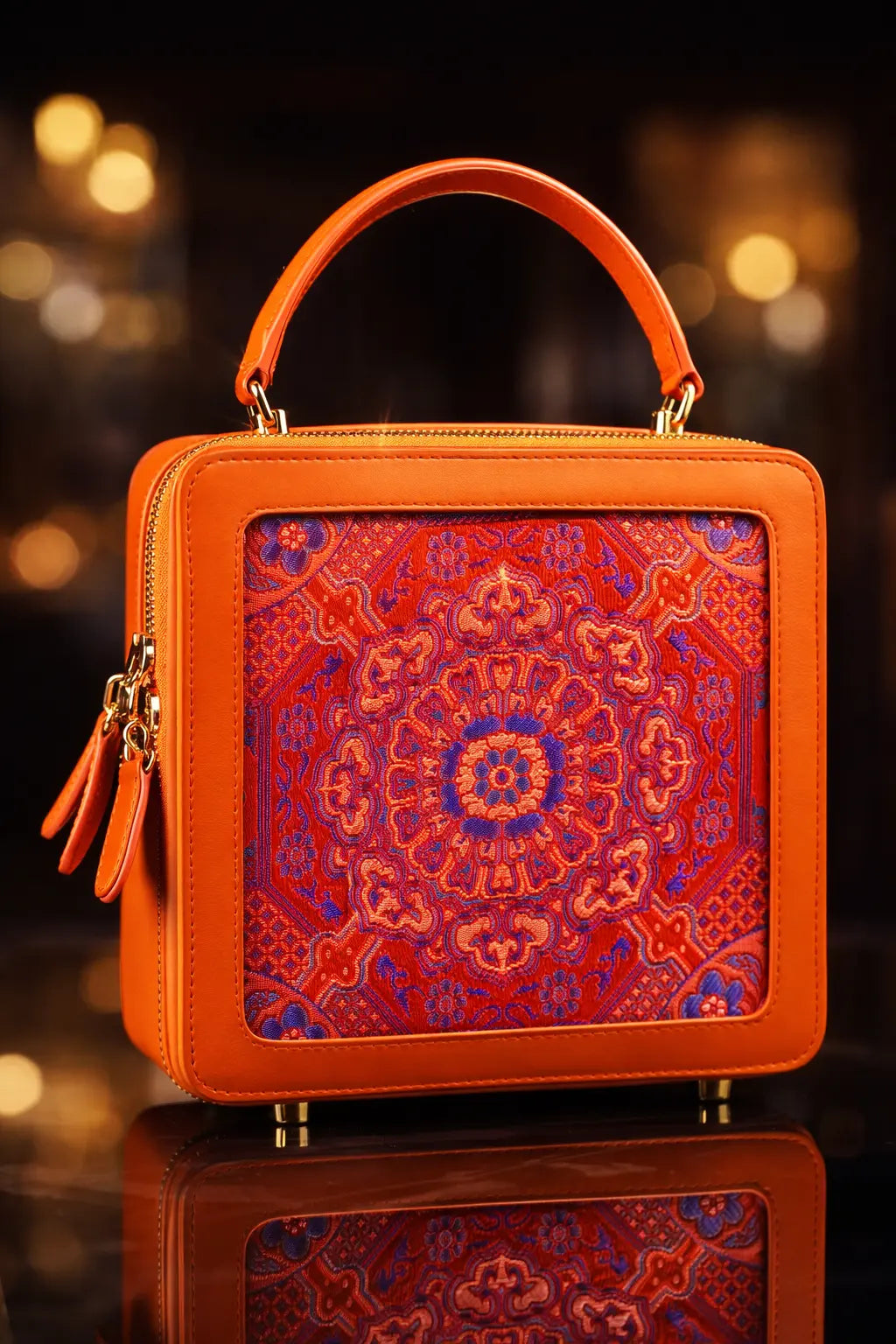„Luxuriöse Echtleder‑Handtasche in kräftigem Orange mit kunstvoller, mehrfarbiger Brokat‑Mandala‑Stickerei in Rot, Violett und Blau; hochwertige goldene Metallfüße und edler Top‑Handle – limitierte Sinodreams Phoenix Arc Bag.