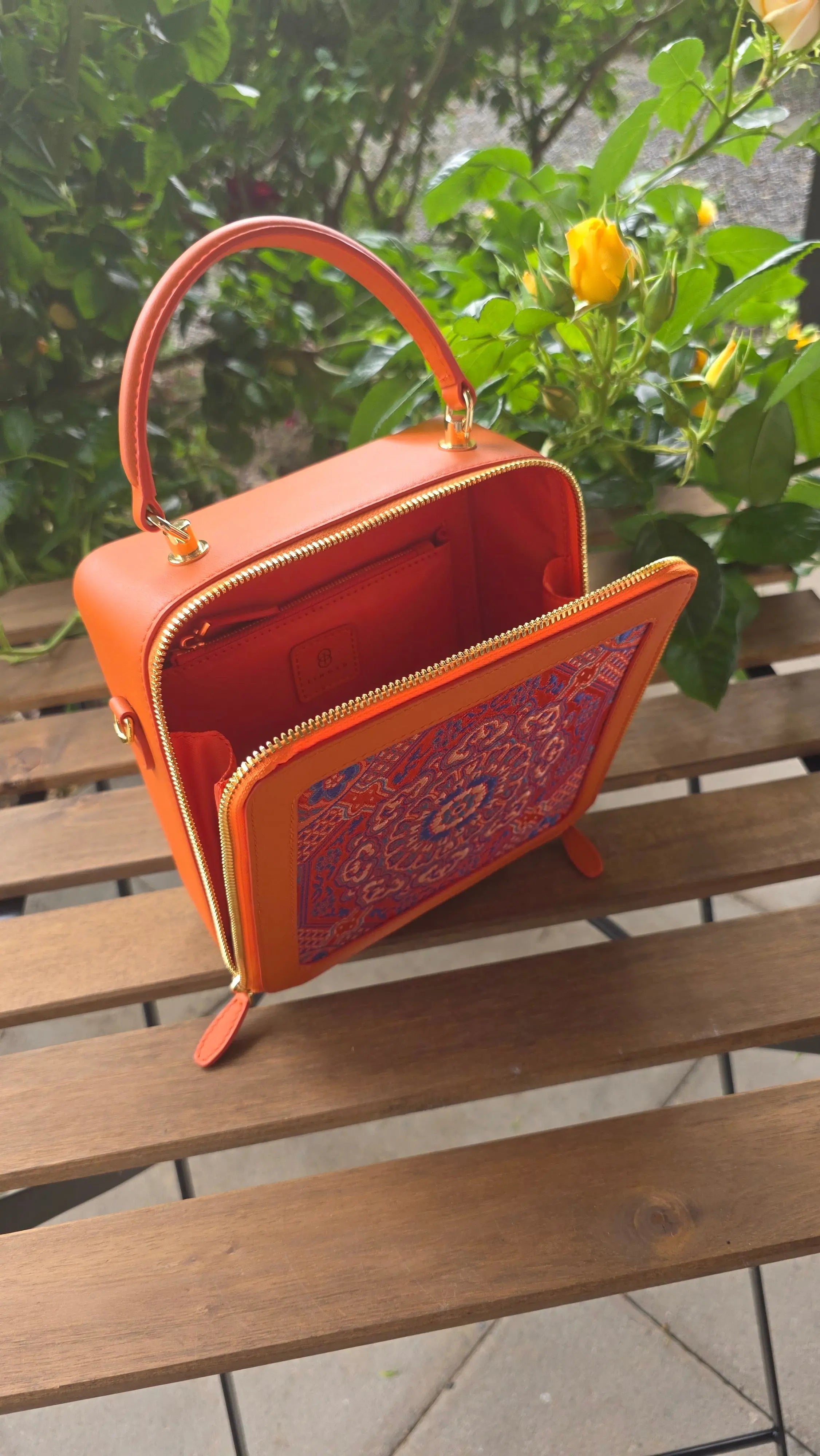 Luxuriöse Damenhandtasche in Mandarin‑Orange, gefertigt aus Echtleder mit kunstvoller Brokatstickerei im Mandala‑Design. Die Tasche zeigt die klare Frontansicht mit Griff und feinen Details der Phoenix‑Kollektion. Grosses innen Raum mit zusätzlichem Fach