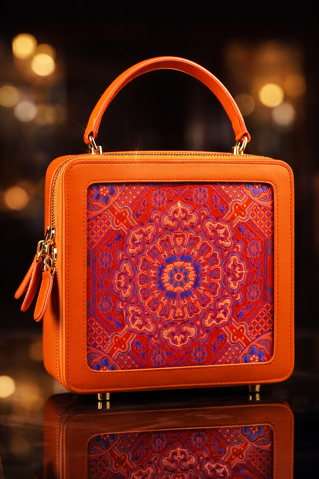 „Luxuriöse Echtleder‑Handtasche in kräftigem Orange mit kunstvoller, mehrfarbiger Brokat‑Mandala‑Stickerei in Rot, Violett und Blau; hochwertige goldene Metallfüße und edler Top‑Handle – limitierte Sinodreams Phoenix Arc Bag.