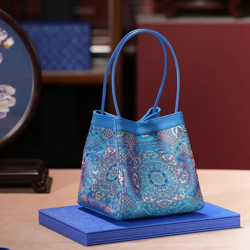ARC Classics – Imperial Sky 
Brokat Blau „Imperial Sky“ mit kunstvollem symmetrischem Muster in Blau, Gold und Violett, Premium‑Ledergriffen und eleganter Arc‑Silhouette.