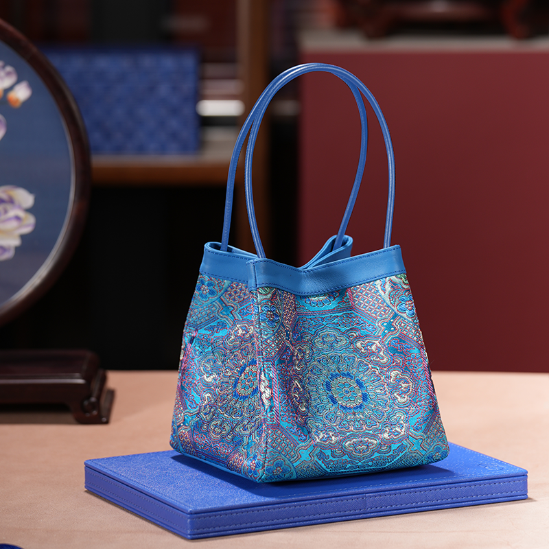 Phoenix Arc Bag – Brokat Blau „Imperial Sky“ mit kunstvollem symmetrischem Muster in Blau, Gold und Violett, Premium‑Ledergriffen und eleganter Arc‑Silhouette.