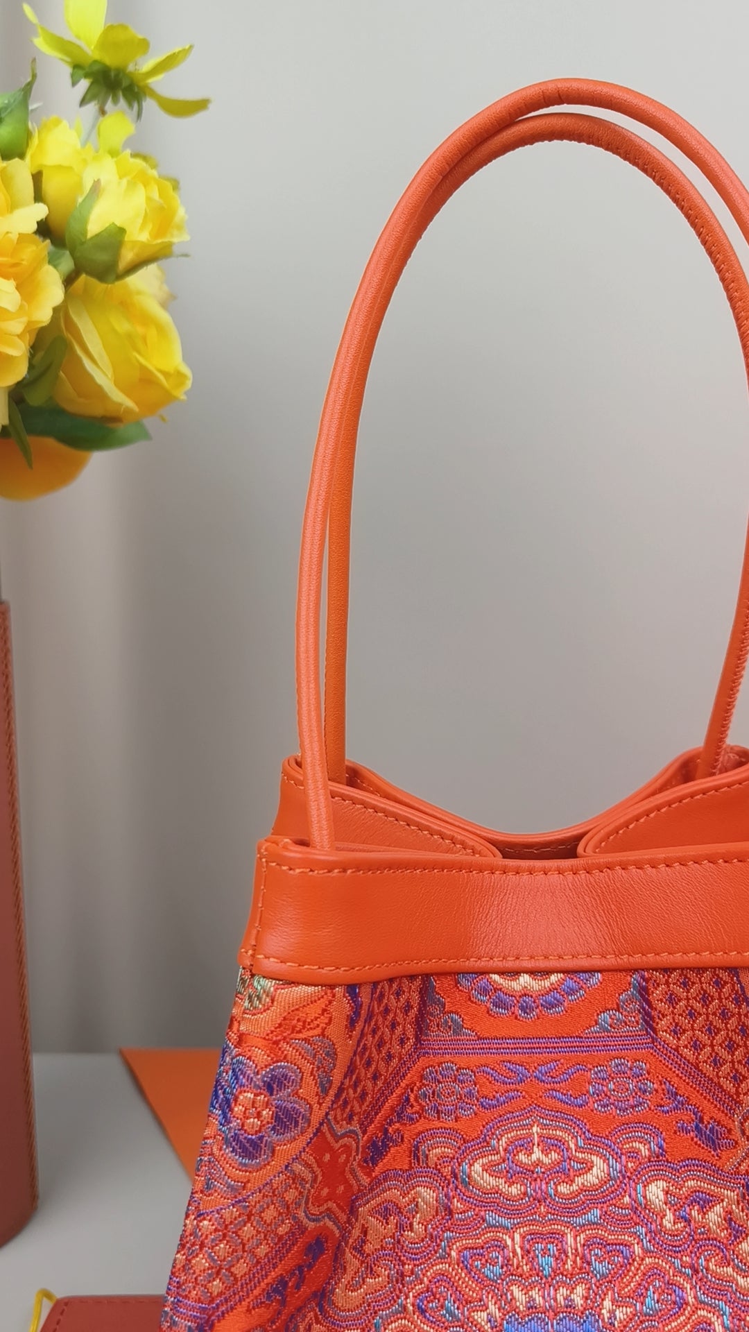 Rote Brokat‑Tasche Phoenix Arc Bag mit kunstvollen gold‑blau‑violetten Ornamenten und eleganter Arc‑Silhouette.