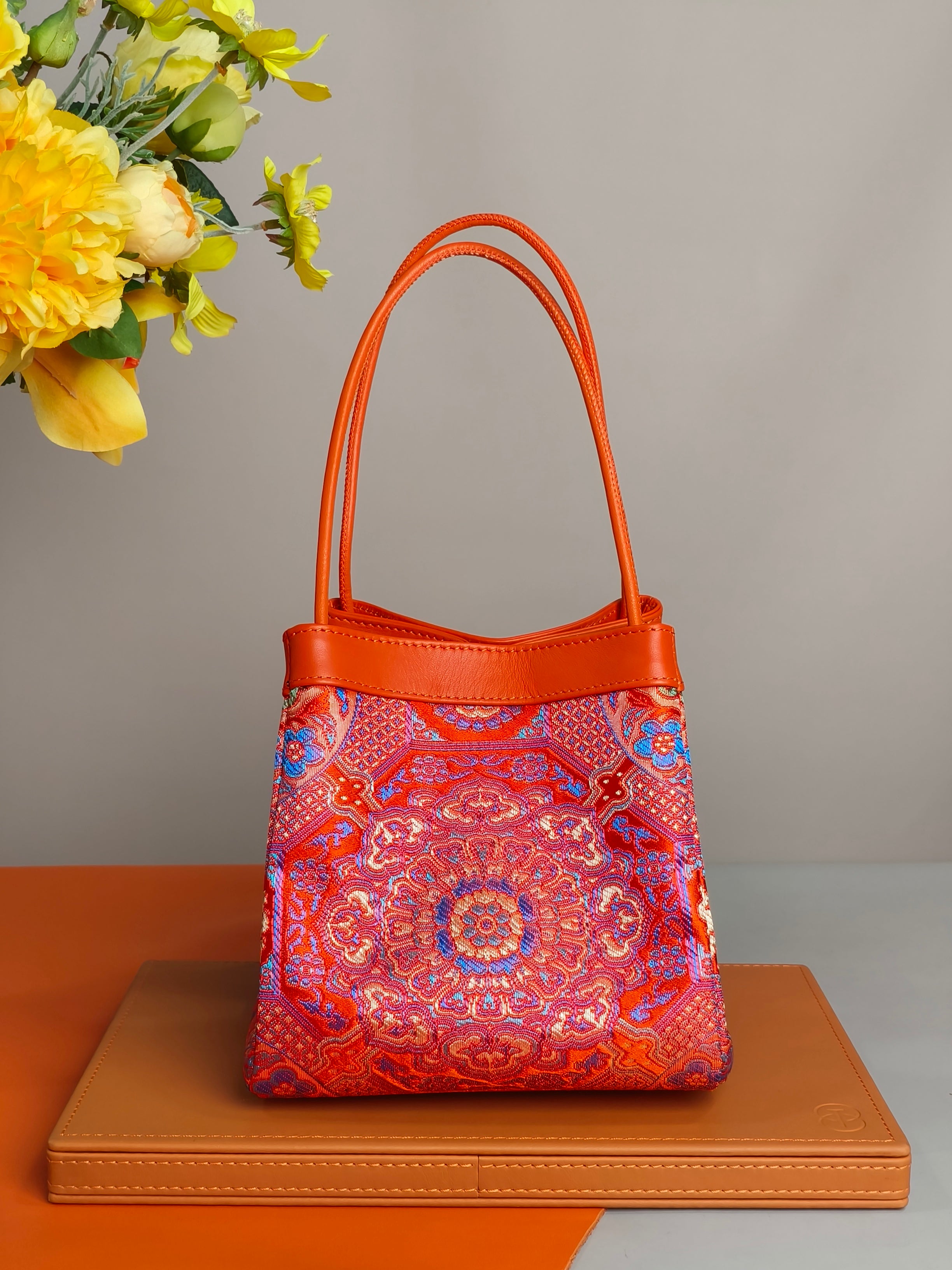 Phoenix Arc Bag in Rot – elegante Arc‑Form aus Brokat mit feinen goldenen Mustern und hochwertigen Lederdetails.