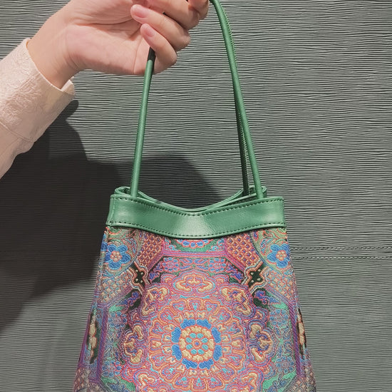 sinodreams jade harmony brokat-handtasche mit blau violett rot gold details und jadegrünem leder an der arc-silhouette video back ansicht