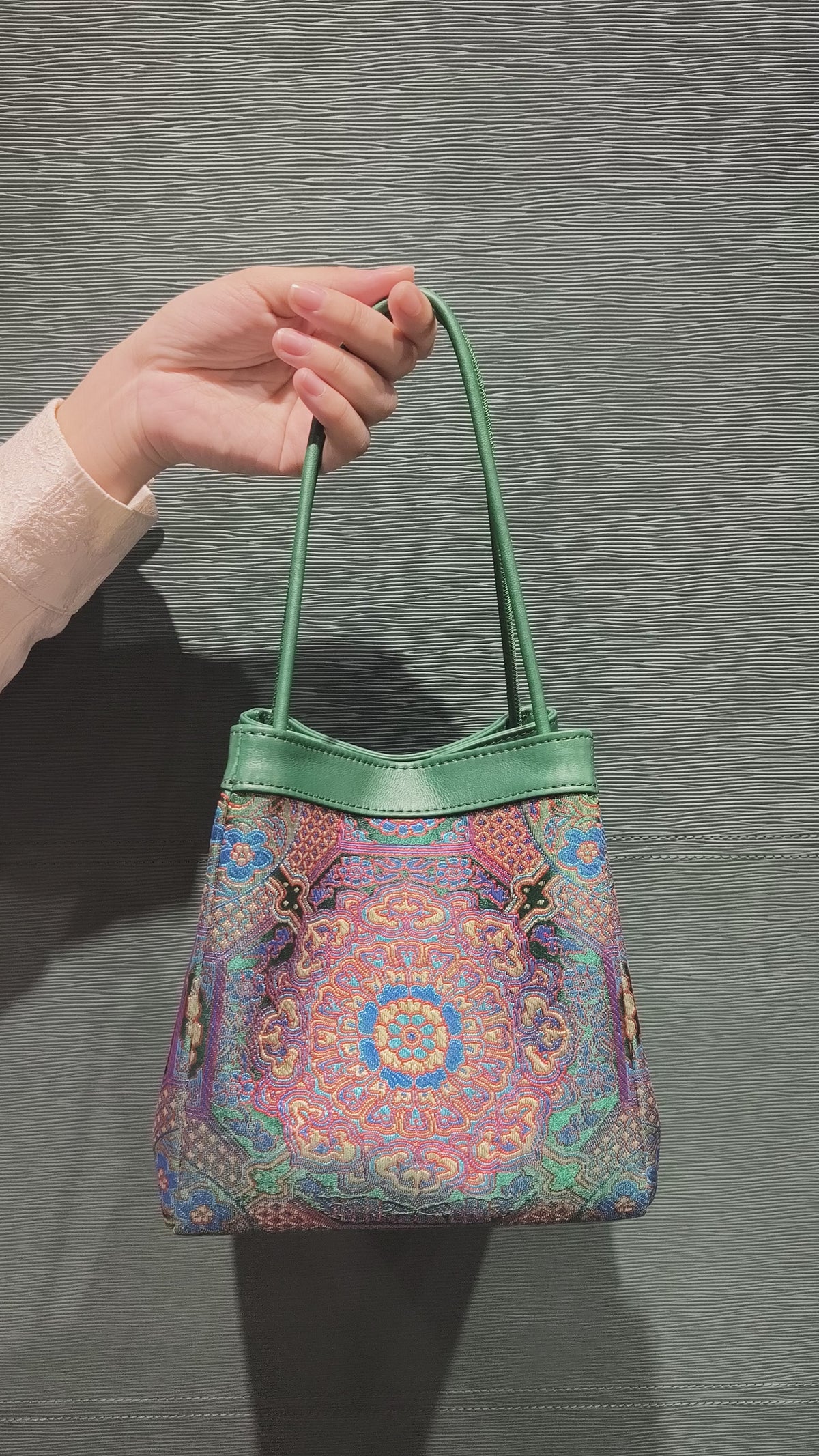 sinodreams jade harmony brokat-handtasche mit blau violett rot gold details und jadegrünem leder an der arc-silhouette video back ansicht